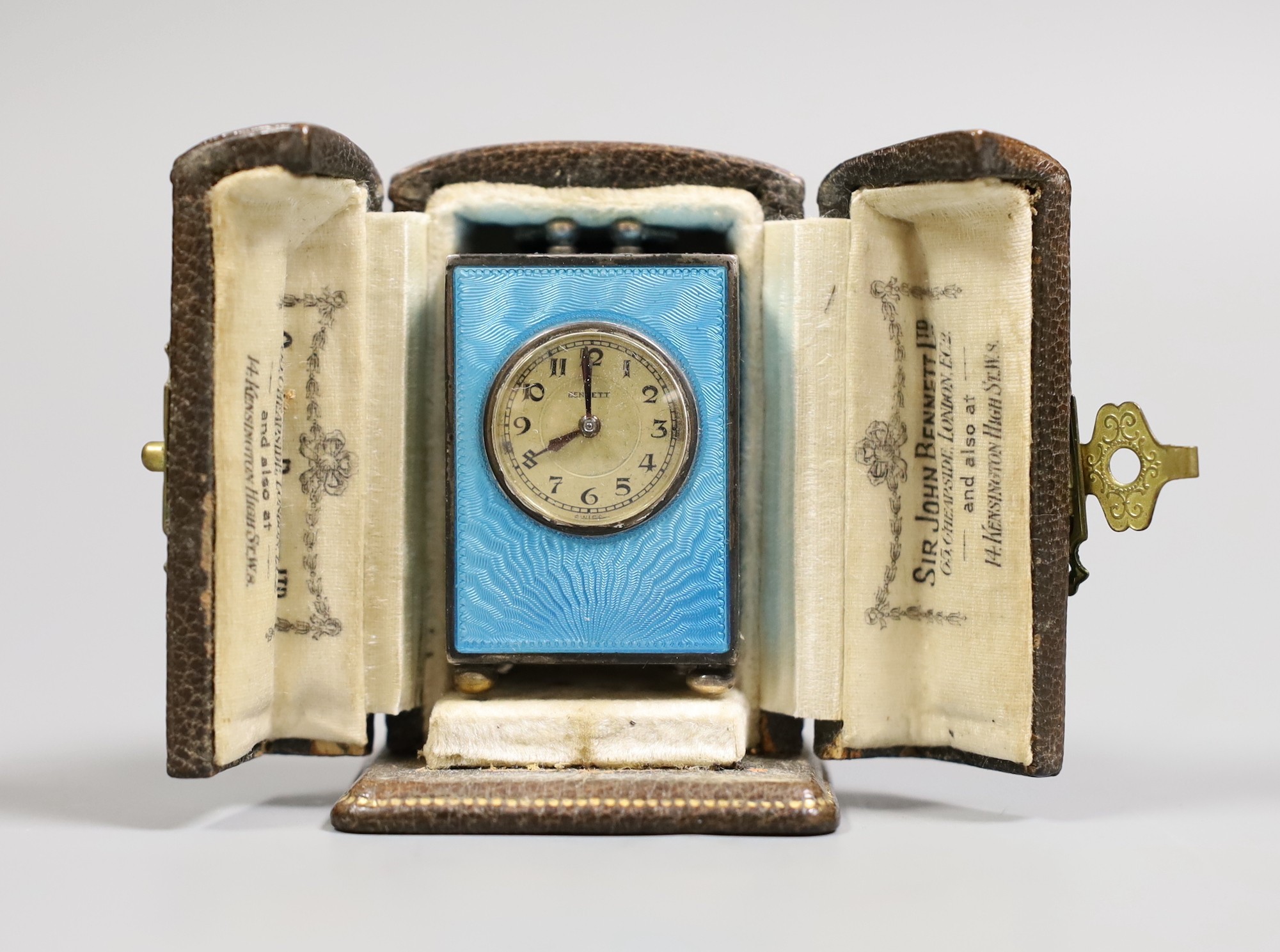 A George V Swiss blue enamel and silver cased miniature carriage timepiece, import marks for Arthur George Rendell, London, 1924, 43mm, on bun feet, in gilt tooled leather carrying case